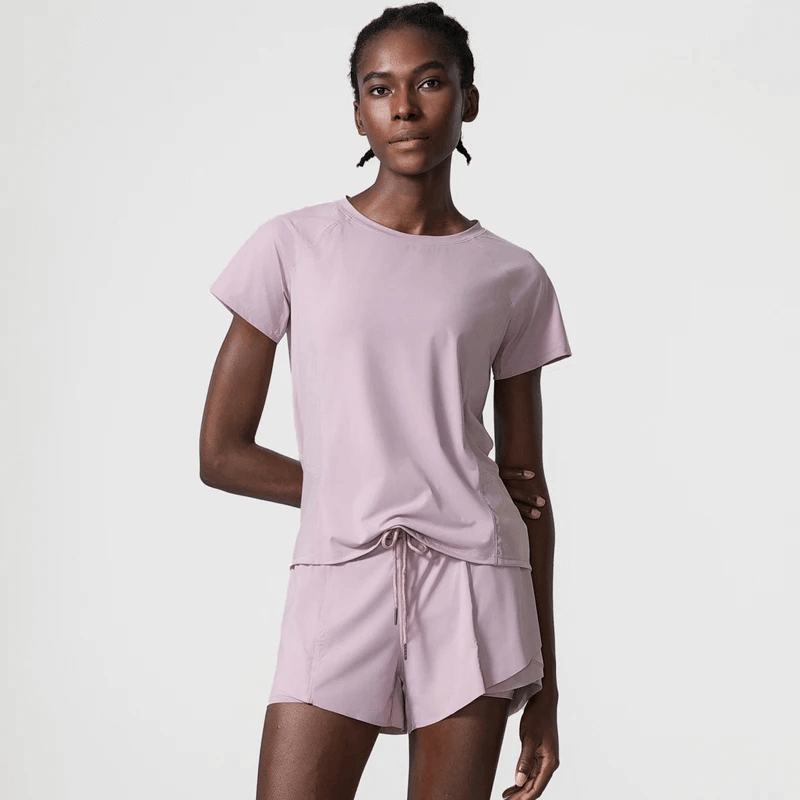 Woman wearing breathable nylon gym wear for yoga, showcasing short sleeves and relaxed fit in soft lavender color.